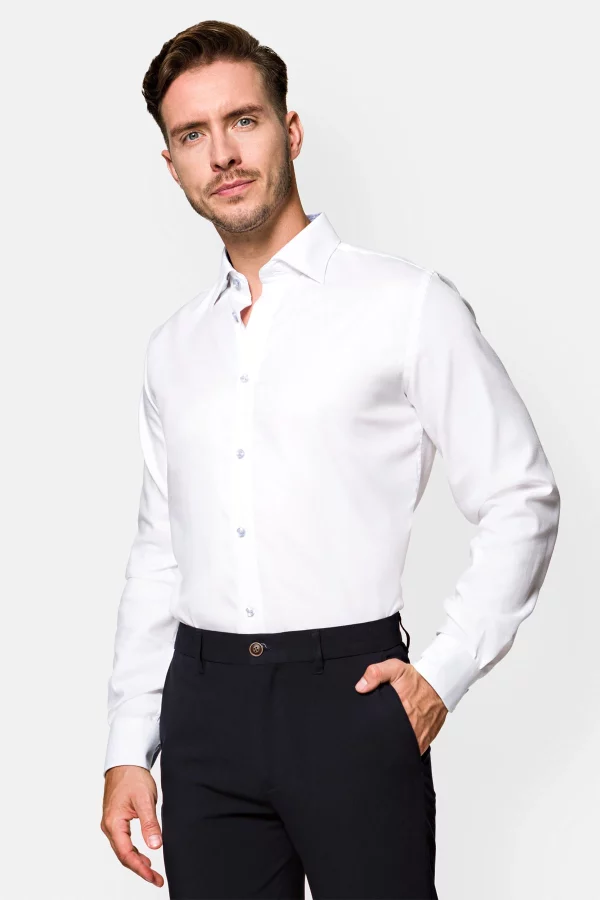 Mężczyzna w białej koszuli, z ręką w kieszeni.