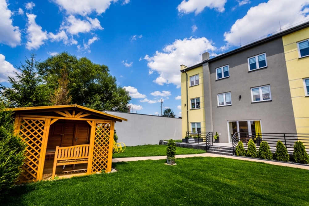 Przed Centrum Opieki i Rehabilitacji MULTISENIOR w Orzechu znajduje się ogród z miejscem do wypoczynku - drewniana altanka zapewnia ochronę przed deszczem lub słońcem w upalne dni