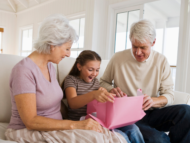Babcia i dziadek obdarowują prezentem 7-latkę