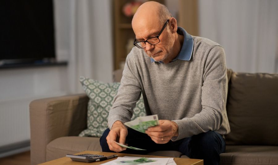 Starszy mężczyzna oblicza otrzymany zasiłek dla chorych na raka.