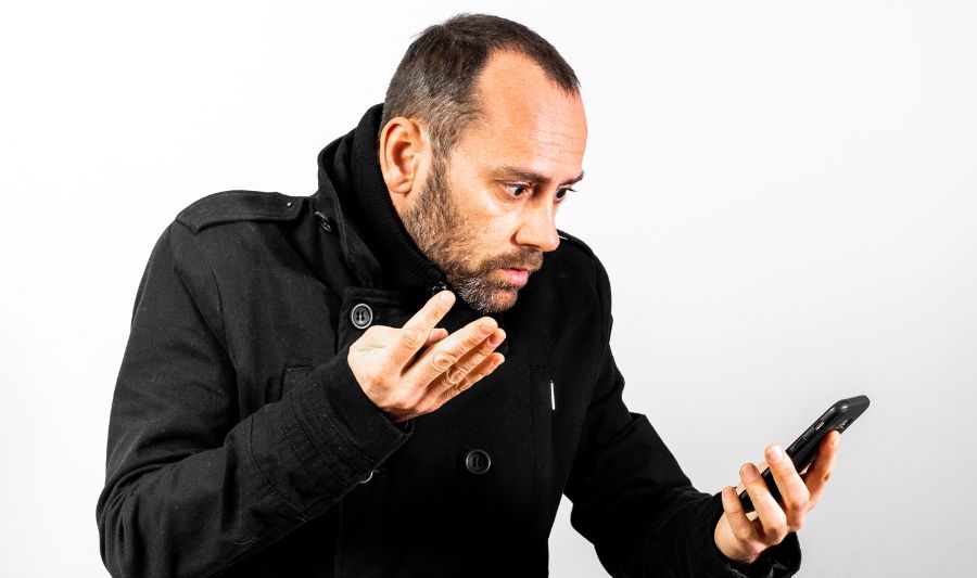 Dojrzały mężczyzna ze smartfonem zauważa, że nie można wysłać wiadomości na Messenger.