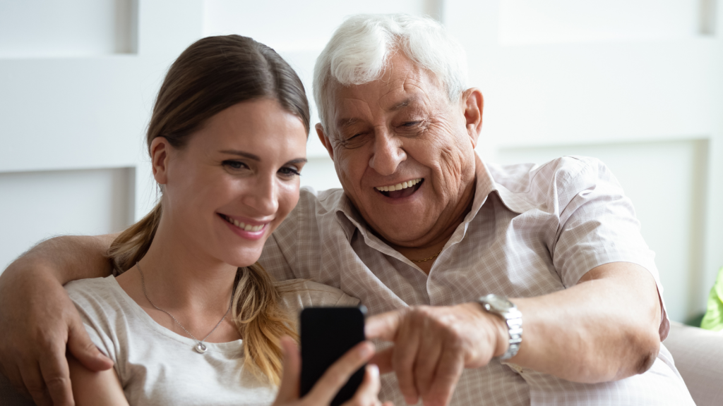 Wnuczka pokazująca telefon dla seniora dziadkowi