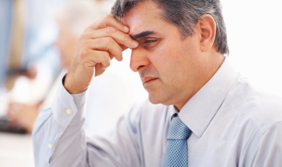 Jak poradzić sobie ze stresem w pracy? Na zdjęciu zestresowany mężczyzna w średnim wieku.
