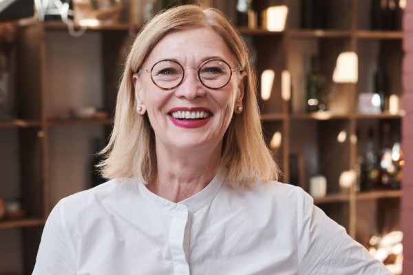 Czy można kochać pracę po 50-tce? Na zdjęciu szczęśliwa, dojrzała kobieta w pracy.