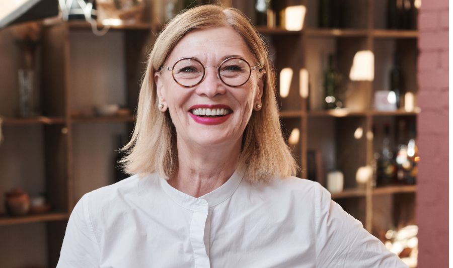 Czy można kochać pracę po 50-tce? Na zdjęciu szczęśliwa, dojrzała kobieta w pracy.