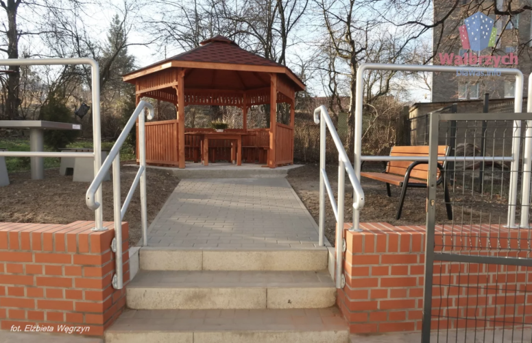 Przed budynkiem Dziennego Domu SENIOR+ w Wałbrzychu znajduje się mini ogród z altaną i ławeczkami